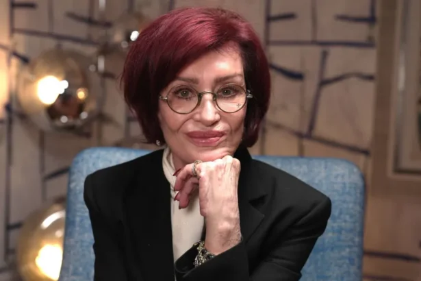 BBC Sharon Osbourne poses with her chin resting on her hand, against a colourful background