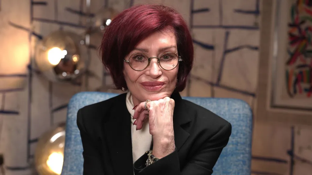 016ed620-cde2-11f1-8443-776dd2459391-jpg BBC Sharon Osbourne poses with her chin resting on her hand, against a colourful background