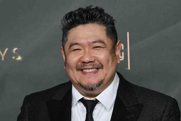 AFP via Getty Images A man in a dark suit with a close-cropped goatee smiles at a premiere