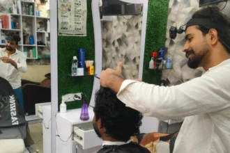 Mohammed Ashim Mohammed Ashim cutting a customer's hair. A headband holds a small camera to his forehead.