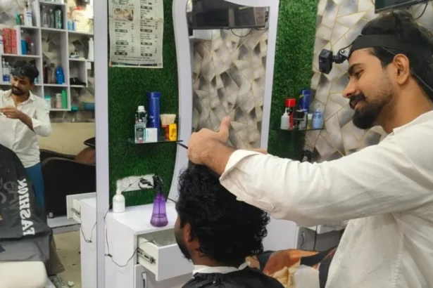 Mohammed Ashim Mohammed Ashim cutting a customer's hair. A headband holds a small camera to his forehead.