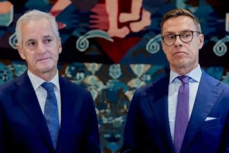 AFP via Getty Images Norway's Prime Minister Jonas Gahr Støre (L) and Finnish President Alexander Stubb wearing navy suits. Støre has a white shirt and blue tie, while Stubb has a white shirt, purple tie and black-rimmed glasses.