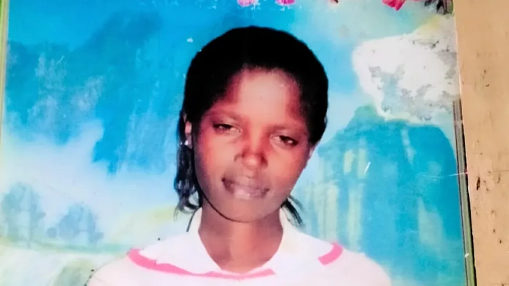 12047420-d2a3-11f1-9aa6-4f9b16403e50-png Rose Wanyua A young woman with dark skin smiling softly in a photo. Behind her is a large blue piece of wall