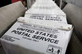 Bloomberg via Getty Images Stacks of United States Postal Service (USPS) flat tubs sit on a conveyor belt