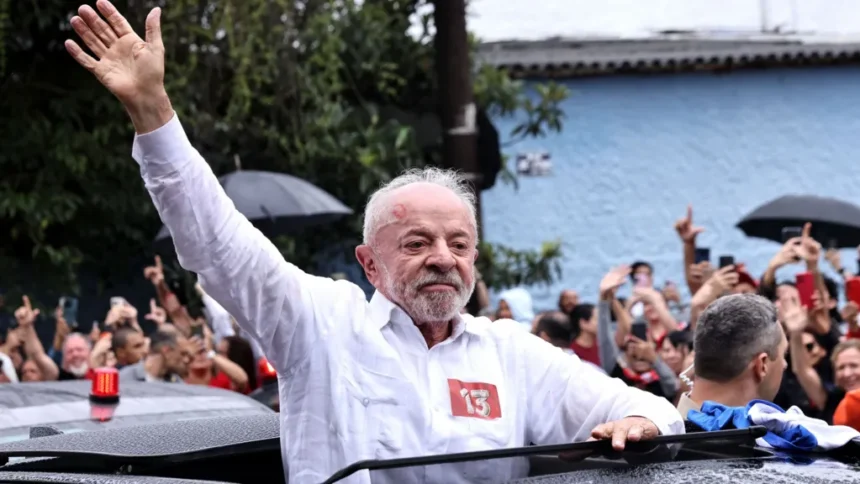 Getty Images Lula is pictured with the upper part of his body from the roof of his car,  wearing a white shirt extends his right arm to greet hundreds of supporters