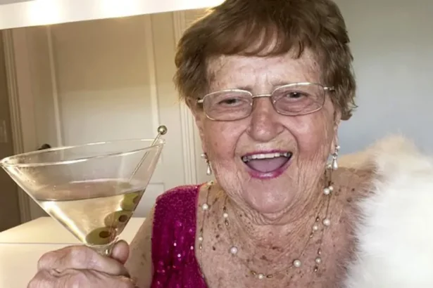 Grandma Droniak Ninety-six-year-old Grandma Droniak, holding a martini glass and wearing a pink sparkly top and a white fur shawl. She is standing in front of a dressing table with lights around the mirror.