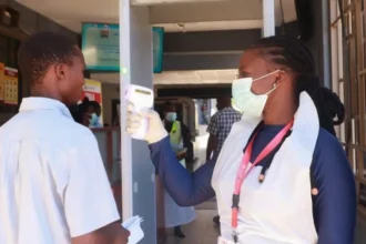 Reuters A female medical worker checks the temperature of a male traveller with a scanner at the Malaba crossing-point between Kenya and Uganda on 8 October