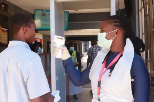 Reuters A female medical worker checks the temperature of a male traveller with a scanner at the Malaba crossing-point between Kenya and Uganda on 8 October