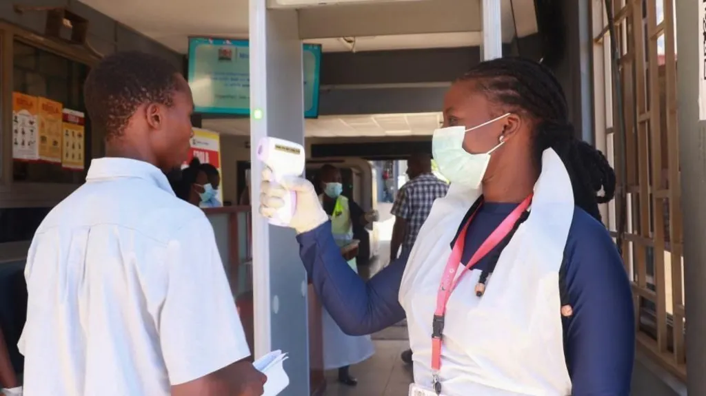 Reuters A female medical worker checks the temperature of a male traveller with a scanner at the Malaba crossing-point between Kenya and Uganda on 8 October