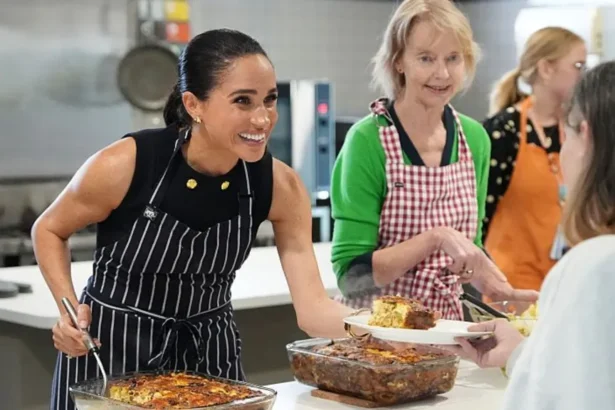 Getty Images Meghan Markle smiles while she serves lunch to a woman