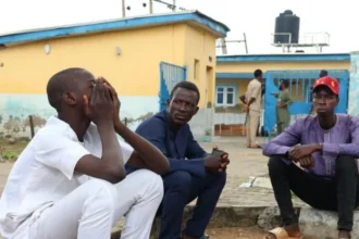 EPA Family members sit outside the General Hospital to reclaim the bodies of their relatives in Minna, Niger State, 18 September