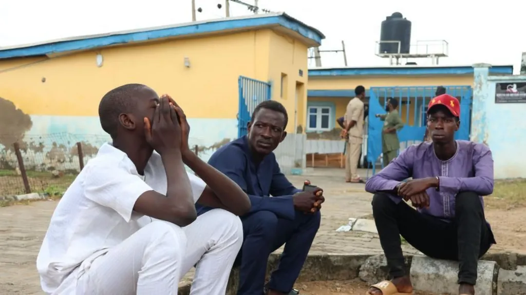 EPA Family members sit outside the General Hospital to reclaim the bodies of their relatives in Minna, Niger State, 18 September