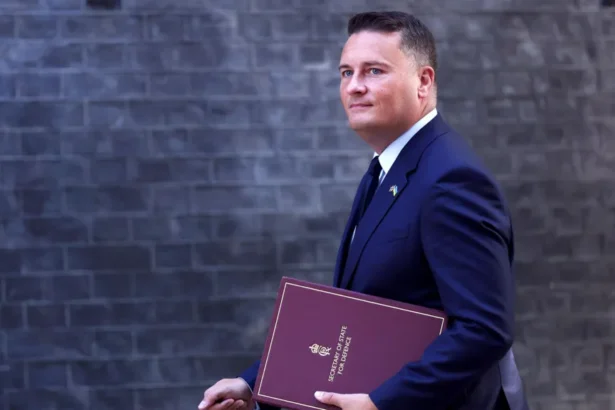 EPA Wes Streeting walks in front of the Downing Street building facade carrying a binder that says 'Secretary of State for Defence' on the front, in September.