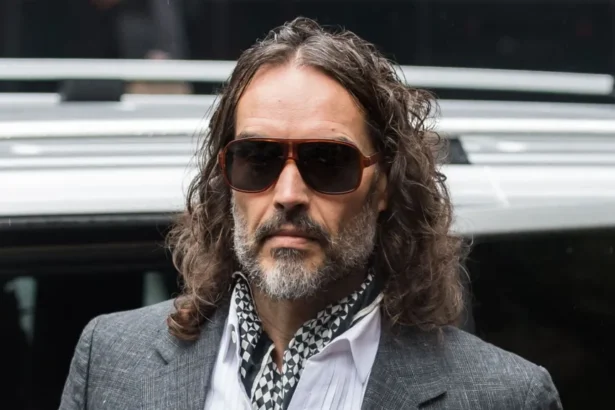 Getty Images Russell Brand arriving at court on Monday 26 October - he is wearing a grey suit jacket, white shirt and black and white cravat. He is also wearing sunglasses.