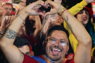 Reuters A bearded and bespectacled Lula supporter raises his arms to make the sign of a heart as he gives a broad smile. He is pictured in front of many other Lula supporters celebrating his victory.