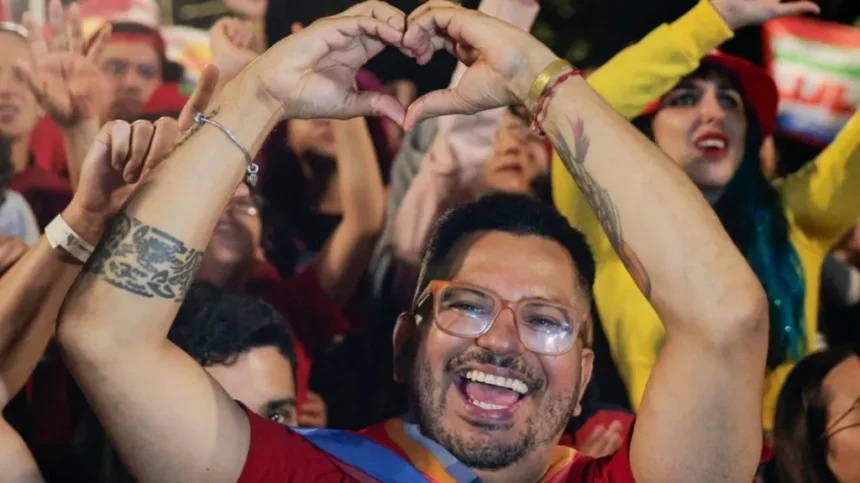 Reuters A bearded and bespectacled Lula supporter raises his arms to make the sign of a heart as he gives a broad smile. He is pictured in front of many other Lula supporters celebrating his victory.