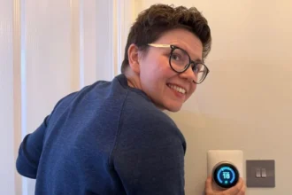 Cora Harrison Cora Harrison, a woman with short brown hair and glasses in a navy jumper, adjusts the temperature on a thermostat to 18 degrees