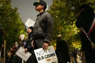 Getty Images A man stands solemnly in a line of people holding anti-racism signs. His sign says 'non au racisme'