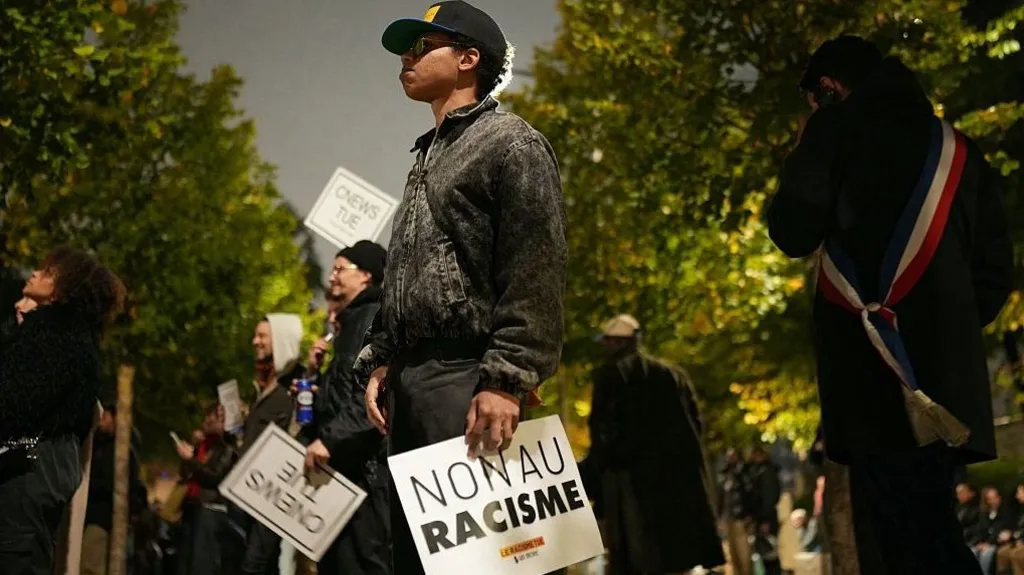 Getty Images A man stands solemnly in a line of people holding anti-racism signs. His sign says 'non au racisme'