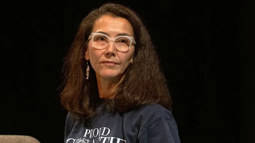 Getty Images Peltola looks to the side as she wears a grey T-shirt and white-framed glasses
