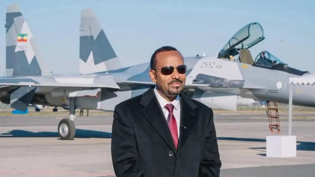 3bba8dd0-d367-11f1-8799-171d5bd36a81-png Abiy Ahmed/Facebook Abiy Ahmed, in a black suit and red tie standing on tarmac in front of a fighter jet