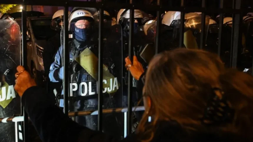 EPA/Shutterstock A woman looks at police officers standing guard outside Poland's Constitutional Tribunal in Warsaw. Photo: 30 October 2026