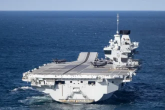 UK Ministry of Defence A large grey carrier is seen on the open ocean.