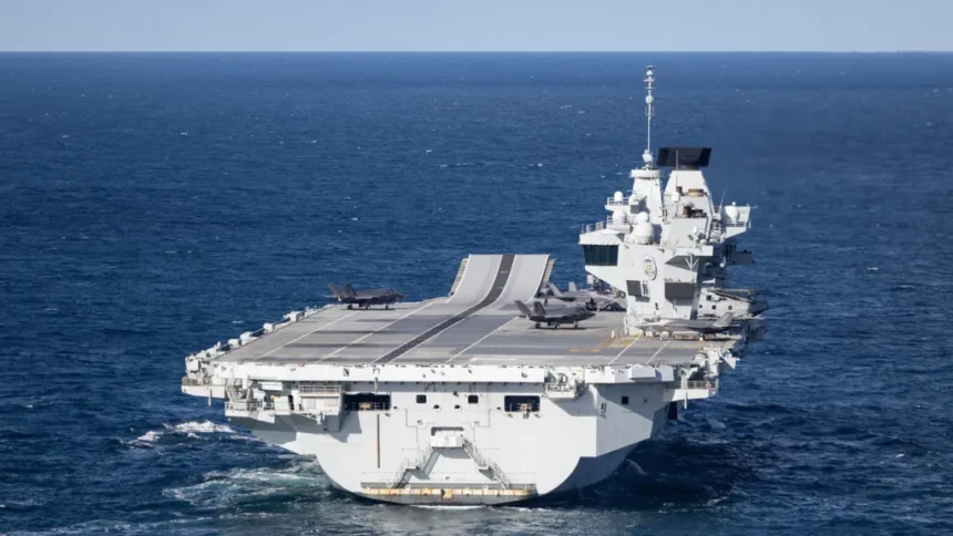 UK Ministry of Defence A large grey carrier is seen on the open ocean.