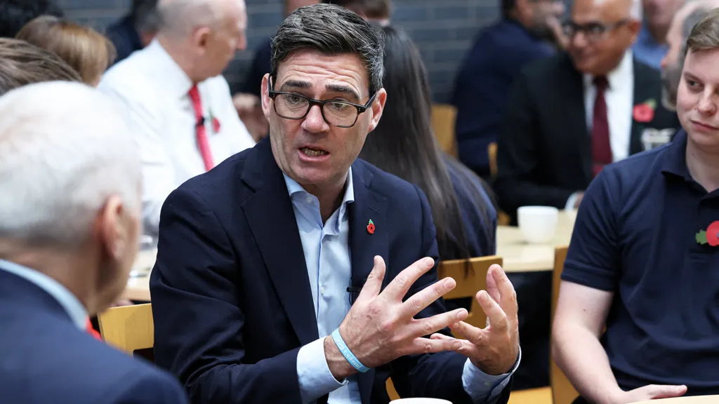 Reuters Andy Burnham sitting at an event in Derby with Chancellor John Healey in the background