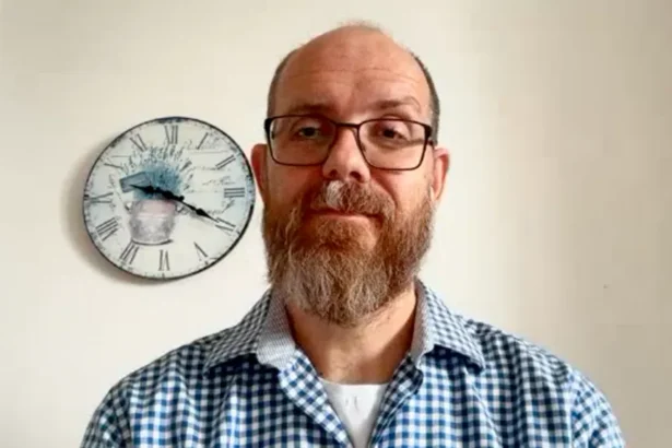 BBC Ondřej Surý looking towards the viewer with a calm expression. He is bald with a beard and wears glasses. He is wearing a smart checkered shirt.