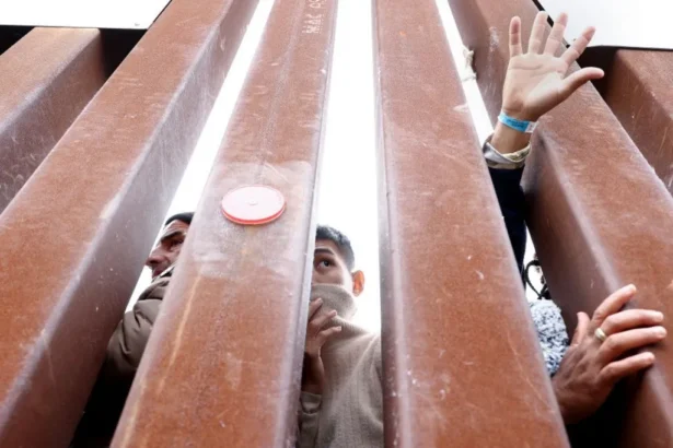Getty Images Immigrants seeking asylum in the US in a makeshift camp between US and Mexico borders reach out through the bars of the barrier. Only half their faces and some hands can be seen through the gaps in the fence.