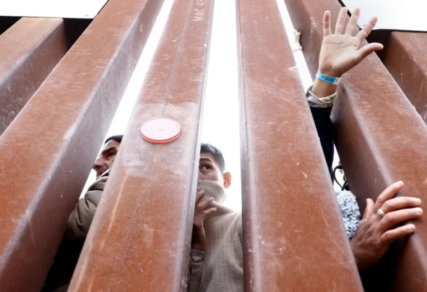 Getty Images Immigrants seeking asylum in the US in a makeshift camp between US and Mexico borders reach out through the bars of the barrier. Only half their faces and some hands can be seen through the gaps in the fence.