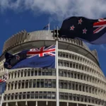 Getty Images New Zealand flags flutter in the wind in clear blue skies with the parliament building in Wellington in the background