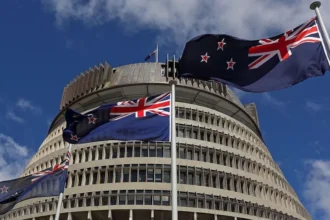 Getty Images New Zealand flags flutter in the wind in clear blue skies with the parliament building in Wellington in the background