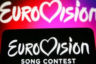 Getty Images Two Eurovision backdrops, one with white words on a pink and red background and the other with white words on a black background in the foreground.