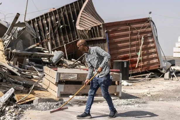 AFP via Getty Images Man sweeps up debris.