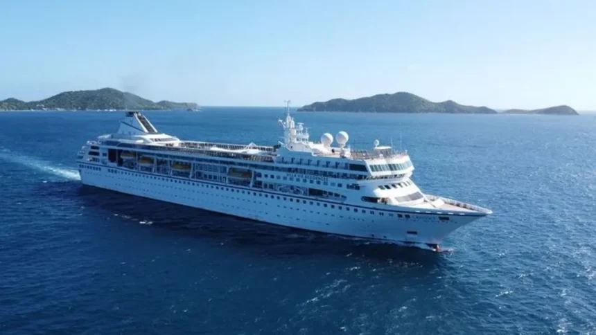 Villa Vie Residences A large white cruise ship sails through deep blue ocean waters near a chain of green, hilly islands under a clear sky.