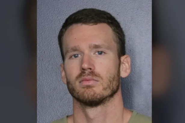 Broward County Sheriff's Office A mugshot of a blonde man with strawberry blonde facial hair and blue grey eyes taken in front of a white wall.