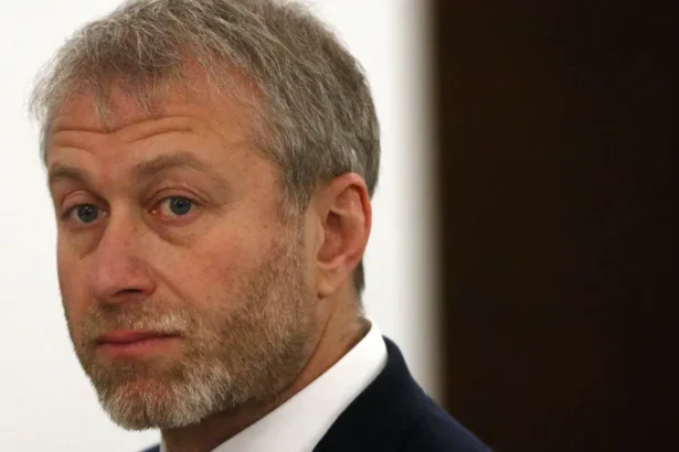 Getty Images Close-up portrait of Roman Abramovich with short grey hair and a neatly trimmed grey beard, wearing a dark suit jacket and white shirt. He is looking slightly over one shoulder toward the camera. The background is softly blurred, with a light-coloured wall and a dark vertical panel visible.