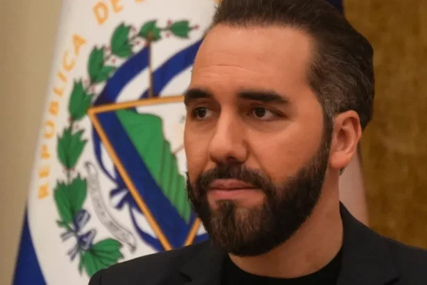 Getty Images Salvadoran President Nayib Bukele wears a black blazer and top during a press conference, with the flag of El Salvador visible behind him.