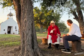 BBC Image shows Father Roy Snipes sitting outside the small, white chapel with the BBC's Gary O’Donoghue