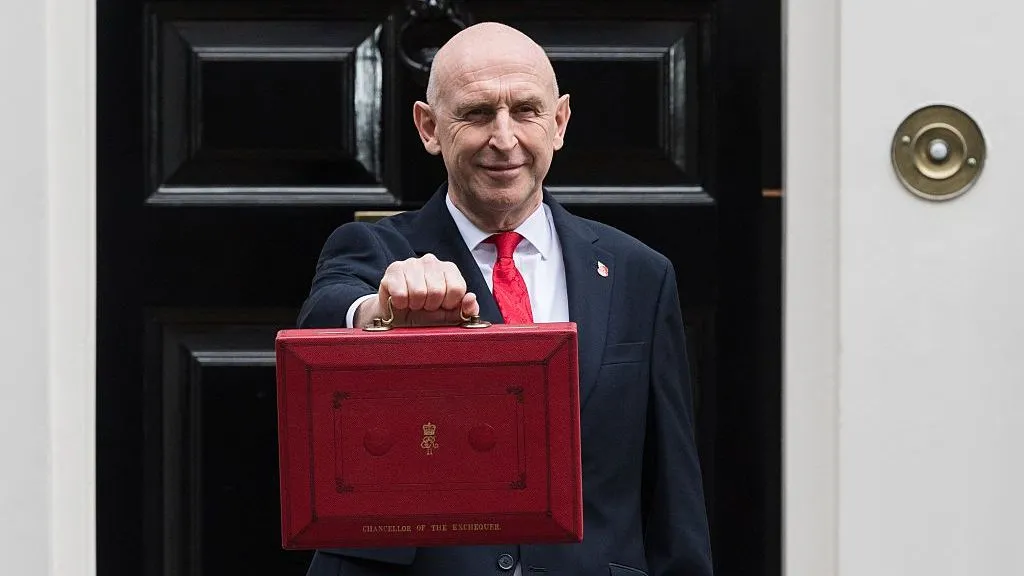 Getty Images John Healy stands in front of Number 11 Downing Street while holding the signature red Budget box.