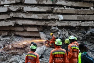 EPA An emergency worker saws through metal and concrete as others watch on at the site of a building collapse in Nairobi.