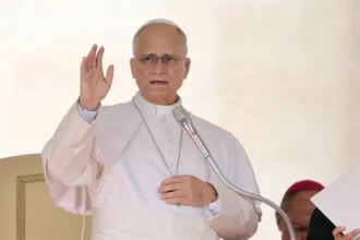 Reuters Pope Leo speaks into a microphone and raises his hand