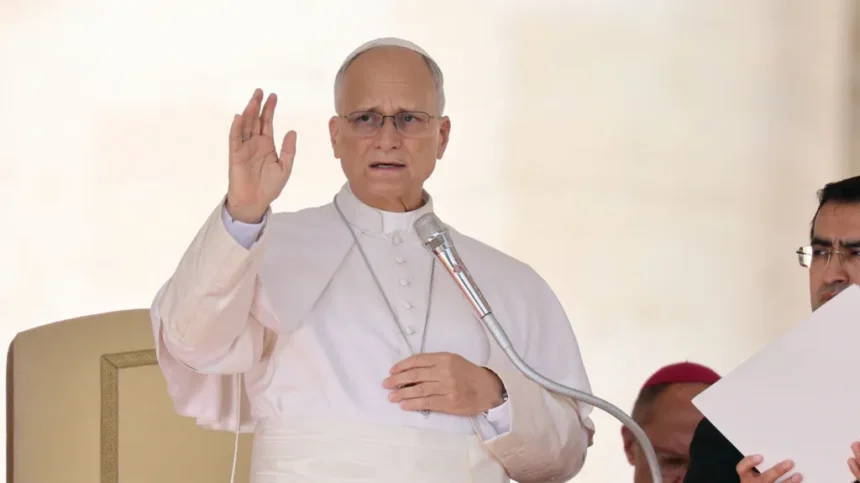 Reuters Pope Leo speaks into a microphone and raises his hand