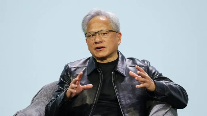BBC Jensen Huang, the CEO of Nvidia, is seated in a grey armchair against a plain, light-blue background.