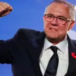 Reuters Doerkson, wearing a suit and tie, pumping his fist in the air with fireworks behind him