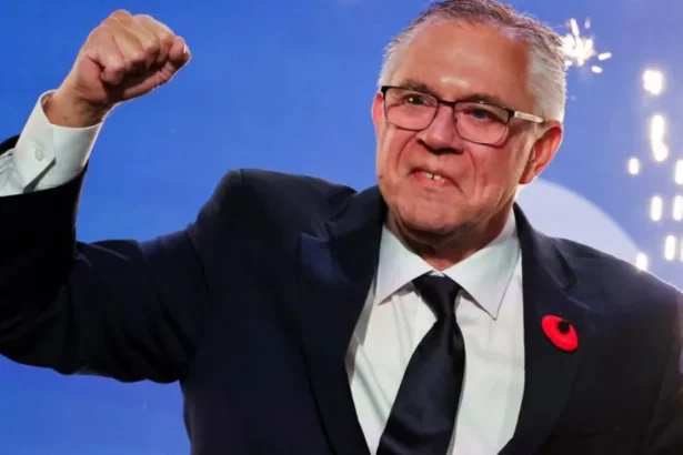 Reuters Doerkson, wearing a suit and tie, pumping his fist in the air with fireworks behind him