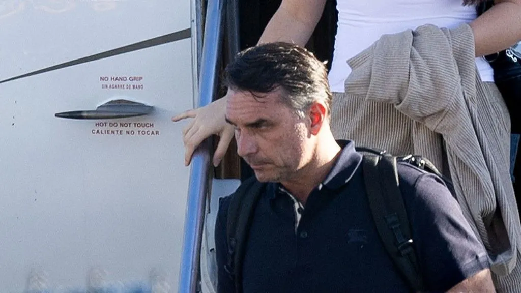 Getty Images Bolsonaro in a dark shirt carrying a backpack as he leaves a plane