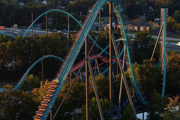 Getty Images Aerial view of large teal and orange rollercoaster, with train car stopped halfway up one of the coaster's peaks